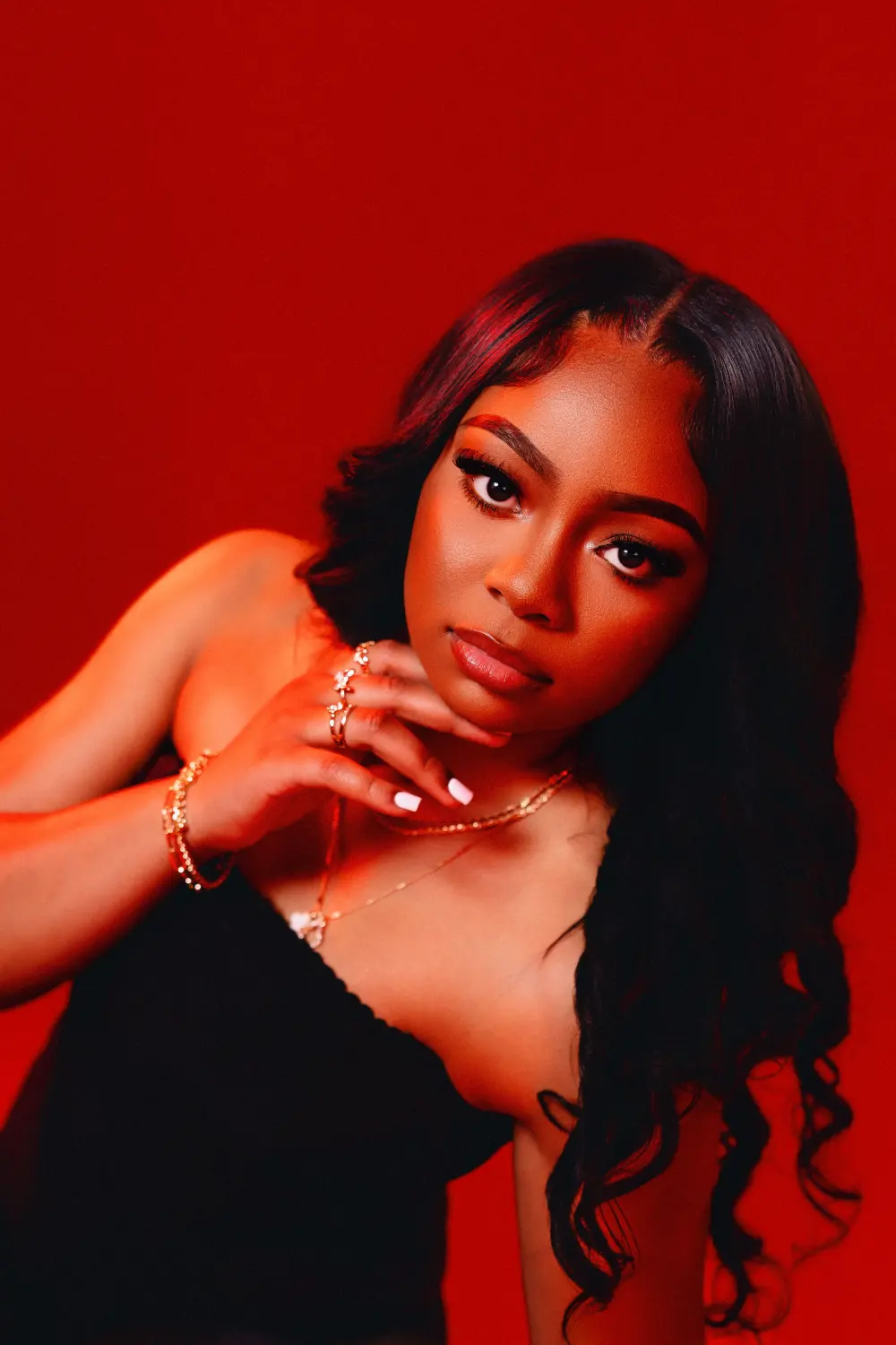 Close portrait of a woman in a black strapless top against a red backdrop