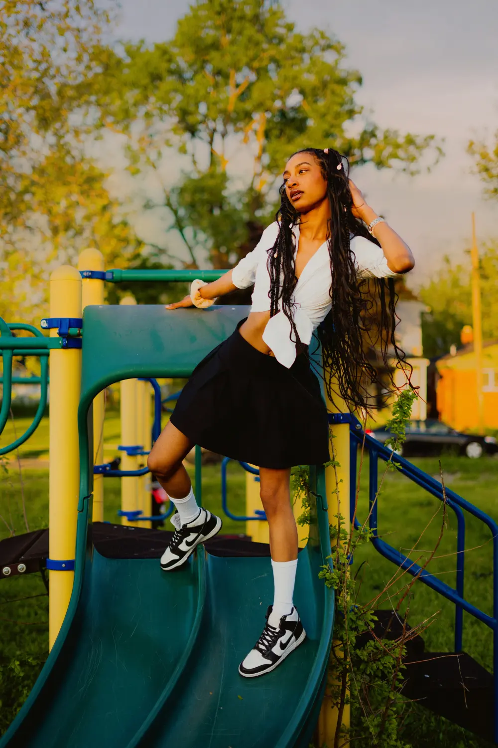 Woman in a white shirt and black skirt climbing an overgrown playground slide