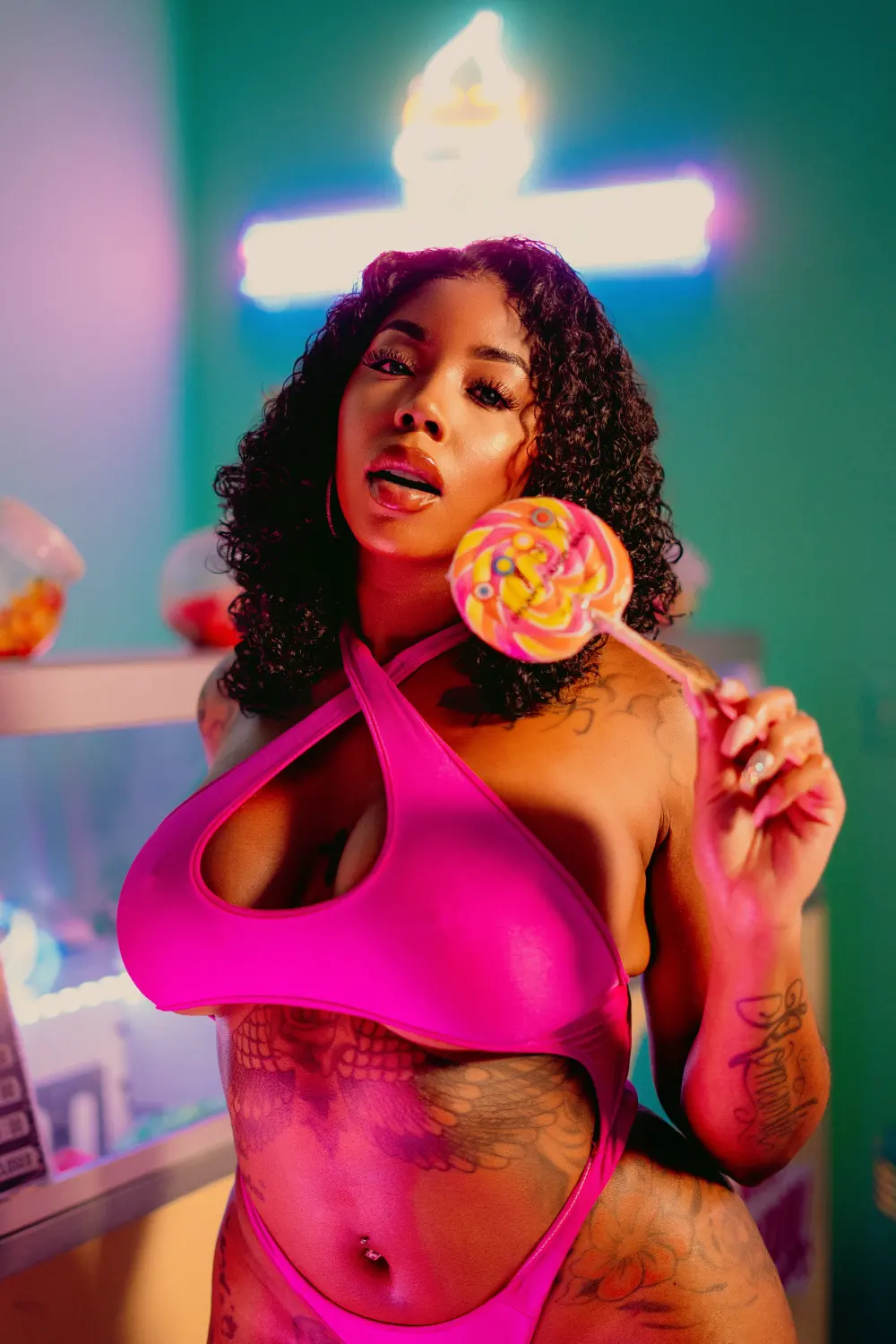 Woman in a pink cutout swimsuit holding a swirl lollipop in a colorful ice cream shop